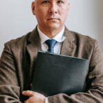 Portrait of a confident professional man holding a notebook, standing indoors.